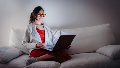 Woman on a couch at home looking at a laptop computer